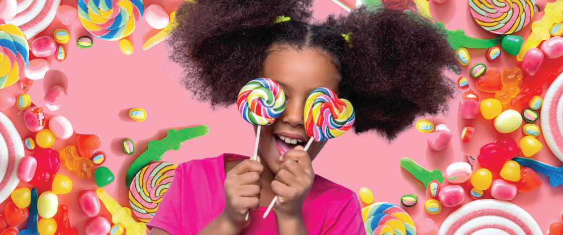 Image of kid holding lollipops in front of eyes and surrounded by candy
